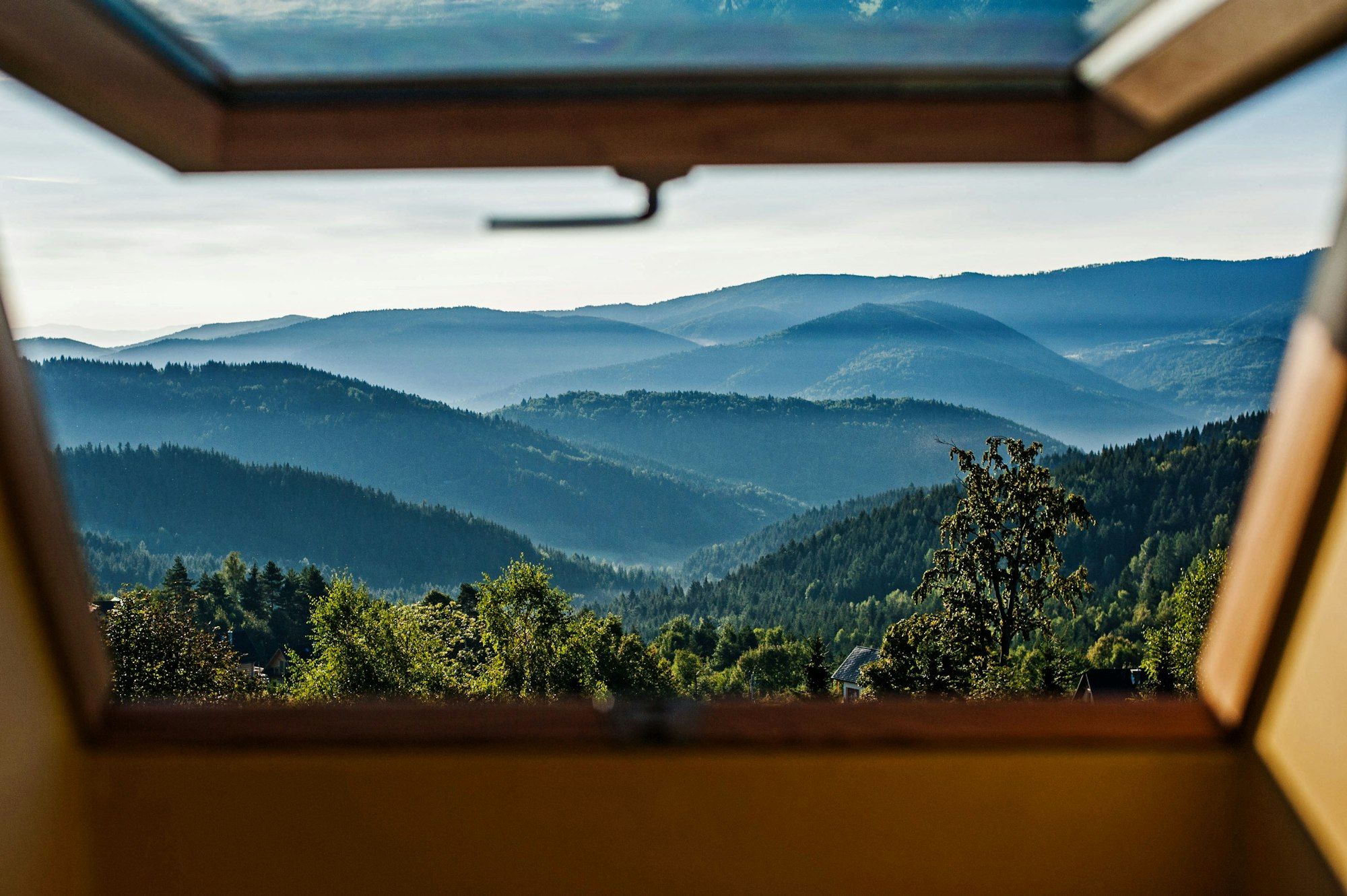 The view from an open window: forested hills in rows of blue, one behind another.
